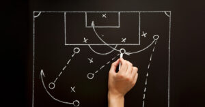 Immobilienverkauf – so finden Sie für sich die richtige Strategie - SATHI-Immobilien Auf einer Tafel werden Spielzüge eines Fußballspiels, also eine Strategie, geplant | Strategie Immobilienverkauf