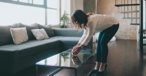 Home Staging – warum es sich jetzt beim Immobilienverkauf lohnt - SATHI-Immobilien Eine Frau dekoriert das Wohnzimmer eines Hauses mit Home Staging, um die Immobilie auf eine Besichtigung mit Kaufinteressenten vorzubereiten | Home Staging